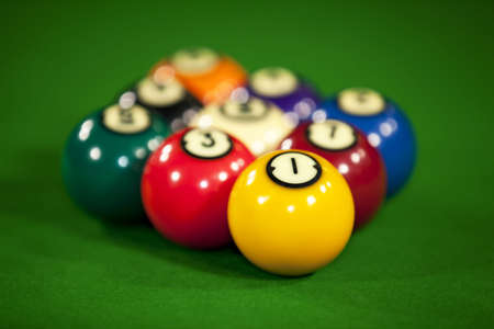 Nine billiard balls on a billiard table with the focus on the yellow ball number oneの写真素材