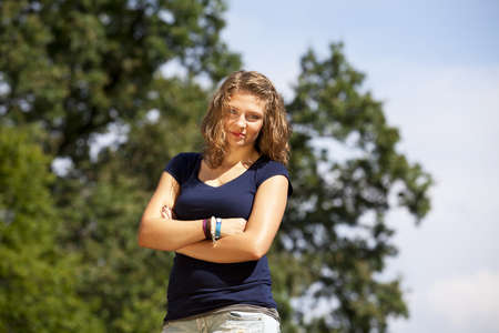 A beautiful blond smiling teenage girl posing with her arms crossed