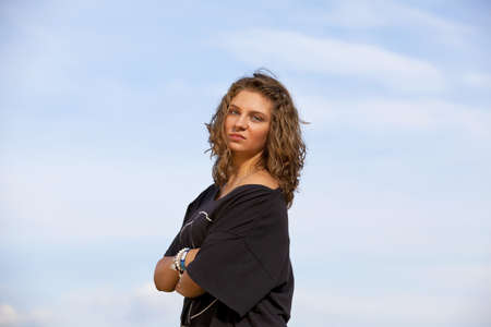 an arrogant looking teenage girl posing with her arms crossed, photographed in the late evening sunの写真素材