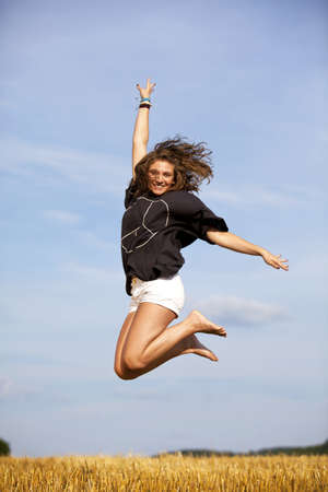 a happy and jumping blond teenage girl photographed during late evening sun on an acre