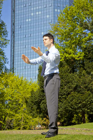 A businessman performing thai chi in a park and relaxing during his lunch break and enjoying the sunの写真素材