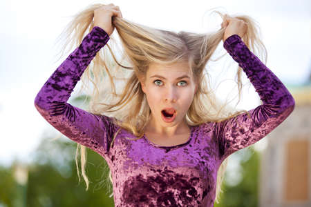 A shocked beautiful blond fashion model tearing her hairの写真素材