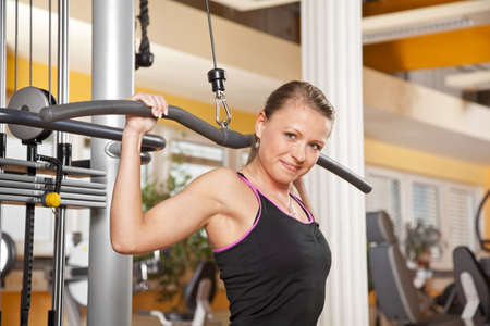 A smiling beautiful young woman in her twenties exercising in a fitness studio training her...