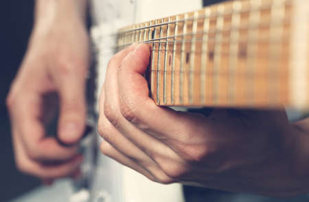 Guitarist playing an electric guitar. Shallow depth of field. Grunge filter.