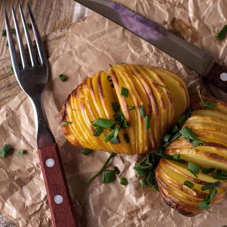 Sliced baked potatoes over wooden background. Rustic style.