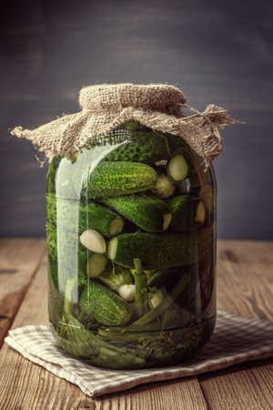 Jar of pickles on wooden table. Salted Cucumbers still-life. Toned.の写真素材