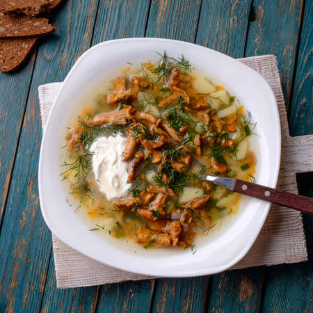 Soup with chanterelles, herbs and potatoes on wooden backgroundの写真素材