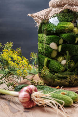 Homemade cucumber preserved in glass jar. Pickles on wooden table.の写真素材