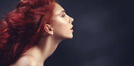 Red-haired girl with flying hair on dark background. Letterbox format.の写真素材