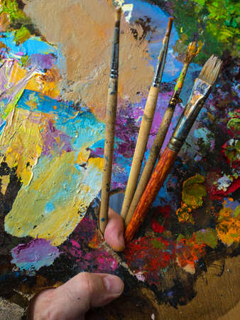Painter holding a palette for mixing oil paints. The color palette close up.の写真素材