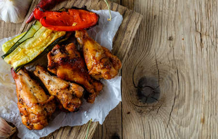 BBQ Wings in sauce with Vegetables on a Wooden Table in a Rustic Style. Copyspace.