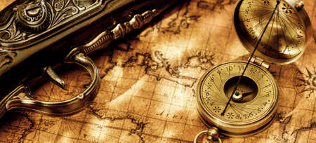 Old vintage retro compass and antique pistol on ancient world map. Vintage still life.