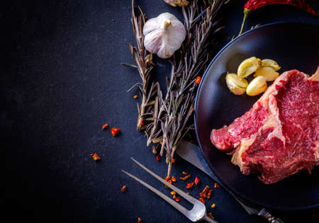 Raw meat steak entrecote on the plate with spice on the dark tableの写真素材