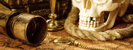 Old vintage candlestick, skull and spyglass on ancient world map. Vintage still life.の写真素材