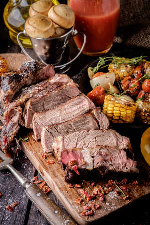 Grilled steak sliced on a cutting board. Entrecote with vegetables on a wooden background.の写真素材