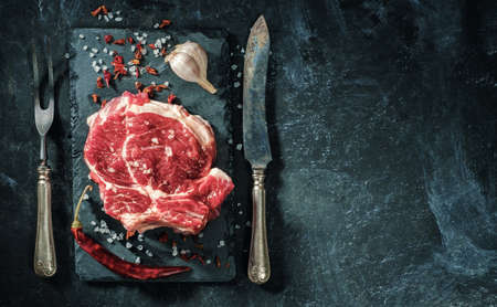 Raw beef steak with salt and herbs on the stone plateの写真素材