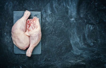 Raw chicken thigh on black stone plateの写真素材