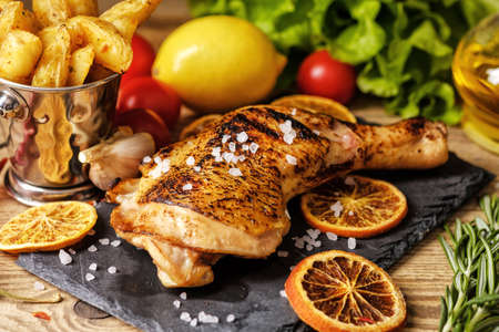 Chicken leg roasted with oranges. Potatoes country style, and cherry tomatoes. の写真素材