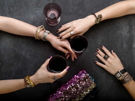 Beautiful female hands with jewelry at the table with glasses of wine. Luxury lifestyle.の写真素材