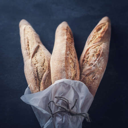 Three freshly baked baguettes on the table, toned image.の写真素材