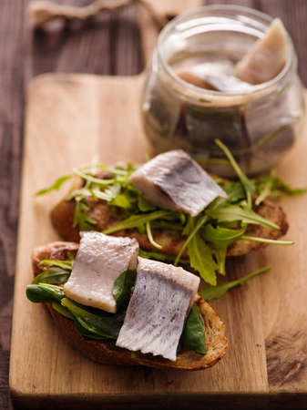 Herring sandwich (traditional Danish smorrebrod) on cutting board.の写真素材