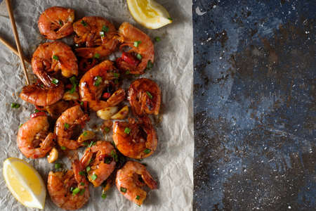 Large grilled BBQ shrimp with sweet chili sauce, green onion and lemon, copyspace.の写真素材