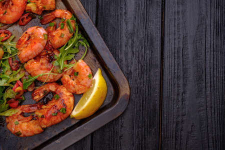 Large grilled BBQ shrimp with sweet chili sauce, green onion and lemon, copyspace.の写真素材