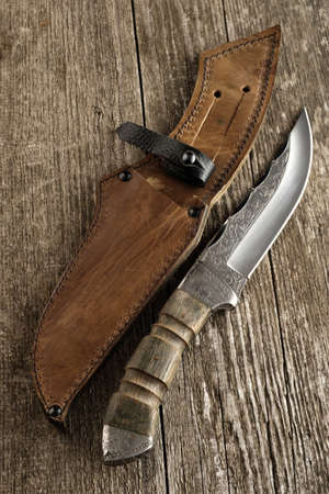 Hunting knife handmade with patterns on the old wooden backgroundの写真素材