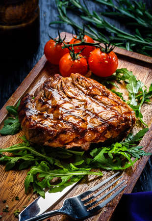 Juicy portions of grilled fillet steak served with tomatoes and roast vegetables on an old wooden boardの写真素材