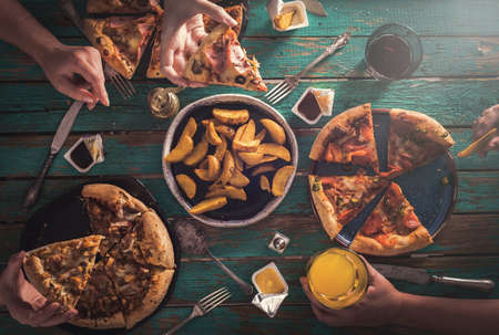 Three young girls eat pizza and drink carbonated drinks. View from above. Friendly Party.の写真素材