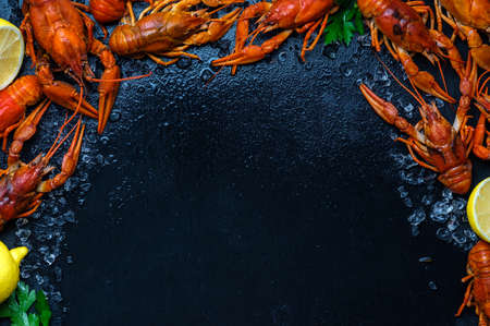 Fresh boiled crawfish with lemons and greens on a dark table with ice. Copyspace for text. Top view.の写真素材