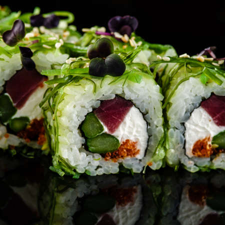 Close-up of traditional japanese sushi on a dark background with reflection. Roll with tuna and greensの写真素材