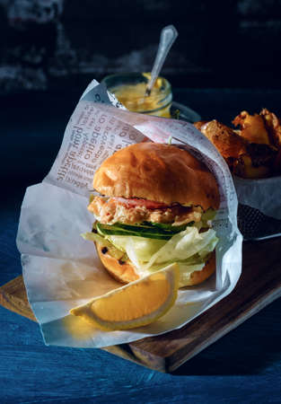 Fishburger with toppings and fries. Rustic style.の写真素材