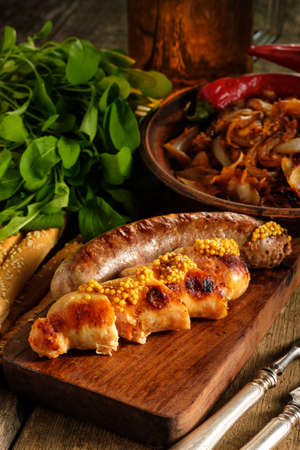 Grilled sausages and stewed cabbage with a mug of beer on a wooden table. Rustic style. Snacks for the Oktoberfest.の写真素材