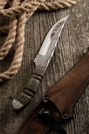 Hunting knife handmade with patterns on the old wooden backgroundの写真素材