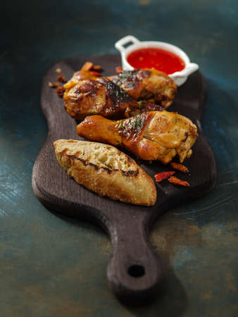Fried spicy chicken legs on the wooden background with the sauce.の写真素材