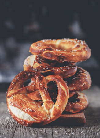 Freshly baked homemade soft pretzel with salt on rustic wooden table. Retro toned image.の写真素材
