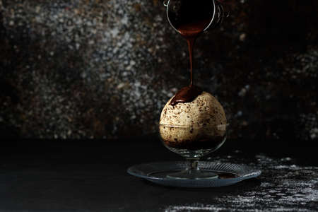Large bowl of ice cream in a glass cup is poured with dark chocolateの写真素材