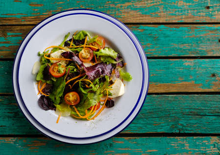 Healthy food. Fresh salad  tomato, cheese and greens, top view, wooden table.の写真素材