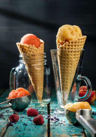 Different sorts of sorbet in waffle cones on a wooden tableの写真素材