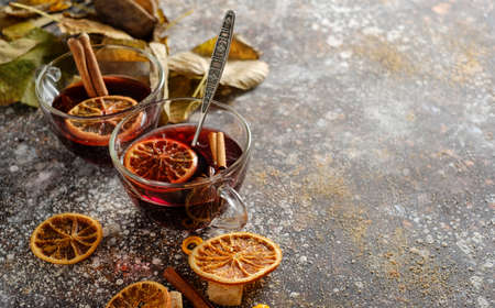 Hot mulled wine with orange, cinnamon, cardamom and anise on darken background. Autumn concept.の写真素材