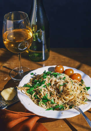 Spaghetti with tomatoes and a bottle of wine on a wooden table. Retro toning.の写真素材