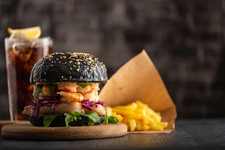 Black burger with fish and shrimps. Fishburger with prawns and French Fries.の写真素材