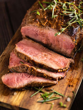 Sliced Roast beef on cutting board with grilled vegetables