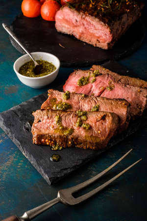 Sliced Roast beef on cutting board with grilled vegetables