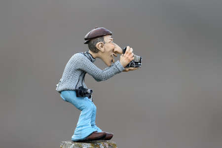 A comic clay figurine of a photographer with an ancient camera shot on a blurred homogeneous backgroundの写真素材