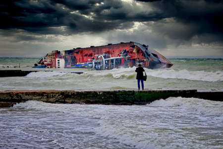 After a severe storm, the tanker was shipwrecked on the popular beach of Odessa, Ukraine. The ship lies on its side directly on the breakwater. Close-up dramatic photo.の写真素材