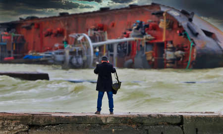 After a severe storm, the tanker was shipwrecked on the popular beach of Odessa, Ukraine. The ship lies on its side directly on the breakwater. Close-up dramatic photo.の写真素材