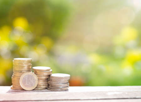 Stick Coin on a wooden table and a pencil placed next to the mountain and nature backdrop. Can think...