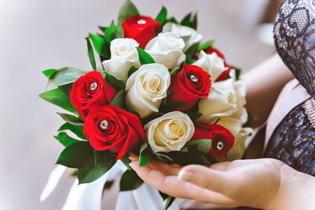 red and white bride's bouquet in hands of brideの写真素材